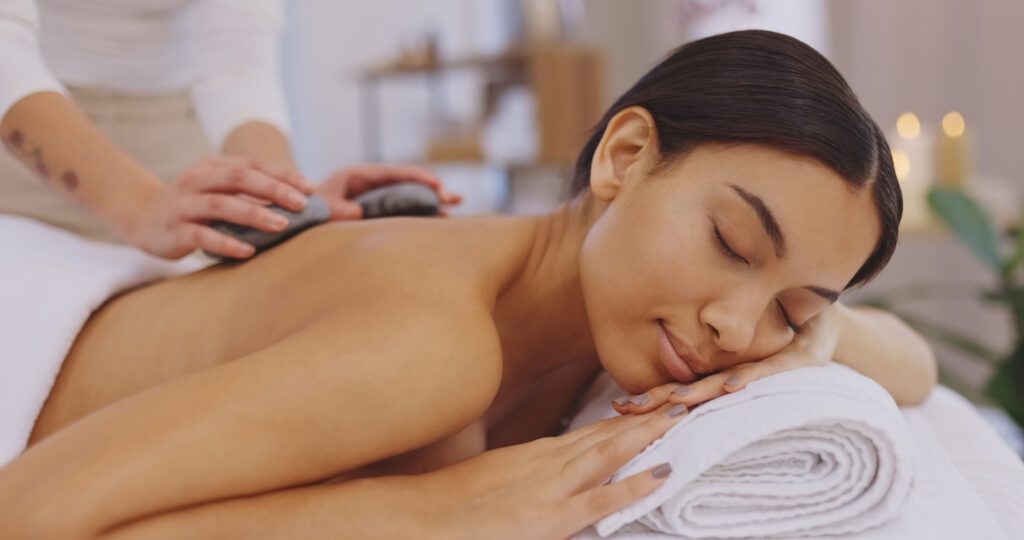 Pretty woman at the spa getting hot stone massage to see how hot stone massage and Himalayan massage differ