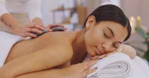 Pretty woman at the spa getting hot stone massage to see how hot stone massage and Himalayan massage differ
