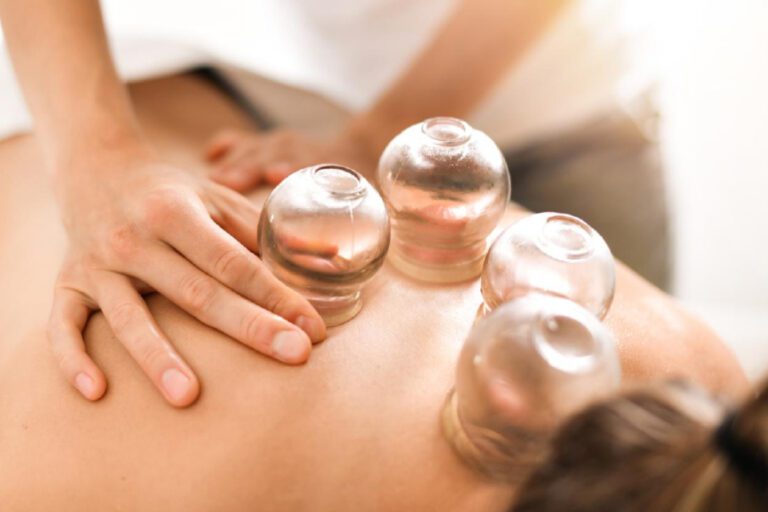 A woman therapist performing a cupping massage to a female client.