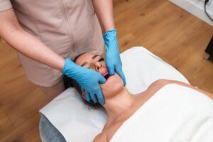 A massage therapist uses TMJ massage therapy to help a woman with jaw pain improve her jaw mobility.