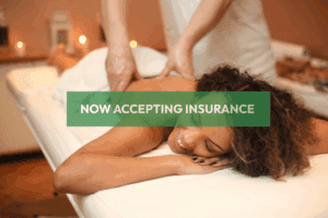 Smiling licensed massage therapist providing back massage to client—Naturally Zuri Massage now accepts NYSHIP and AETNA insurance.